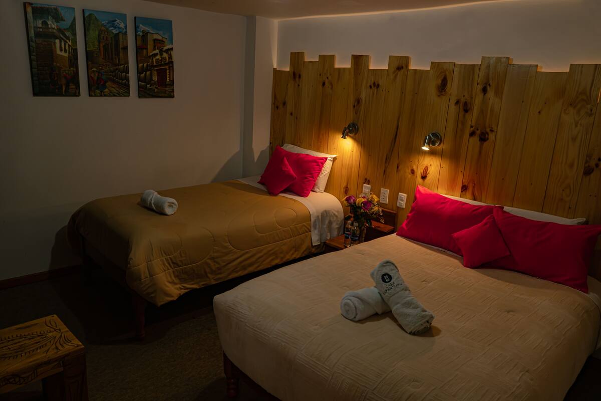 Ein Hotelzimmer mit zwei Betten, einem Holzkopfende, einem Bild an der Wand und einem kleinen Tisch mit einer Vase.