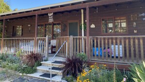 Een houten chalet met een veranda, trappen naar de ingang en een 'Welcome'-bord.
