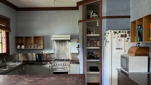 Een keuken met een centraal eiland, houten stoelen, een fornuis en een koelkast.