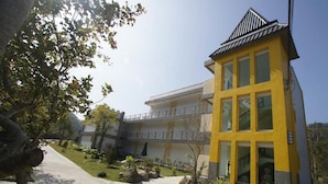 Ein gelbes Gebäude mit Balkon und einem Weg davor.