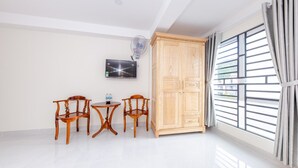 A room with a wooden wardrobe, a TV mounted on the wall, and a large window with curtains. - OYO 572 The Wanda Hotel (Nam Nha Trang)