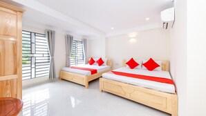 A hotel room with two wooden beds, white bedding, red pillows, a wooden wardrobe, and a large window with curtains. - OYO 572 The Wanda Hotel (Nam Nha Trang)