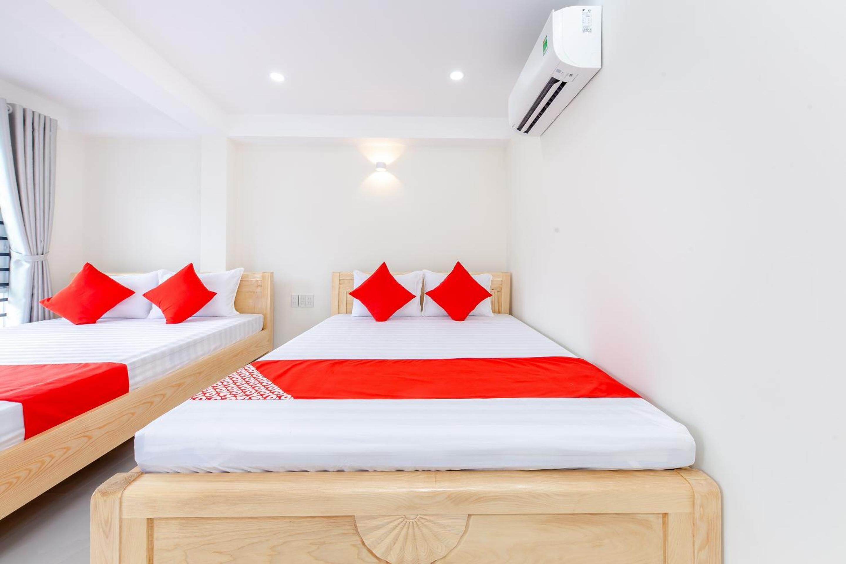 A hotel room with two beds, each with red and white bedding, and a wooden headboard.