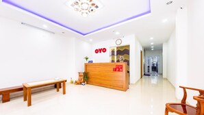 A reception area with a wooden reception desk, a bench, and a chair. - OYO 572 The Wanda Hotel (Nam Nha Trang)