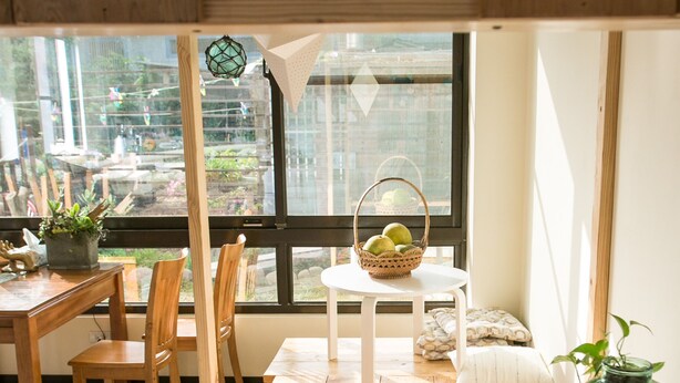 A wooden dining table with chairs, a small white table, and a basket of apples. - Tree House Café & Homestay (Tongluo)
