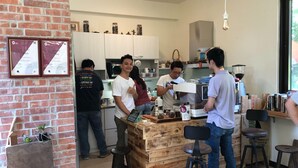 A cozy kitchen with a wooden bar, stools, and a brick wall. - Tree House Café & Homestay (Tongluo)