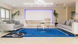 Un hall d’entrée moderne avec deux canapés, une table basse et un tapis bleu orné du mot « SOUTH ».