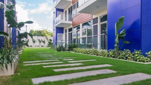Un bâtiment moderne à la façade bleue, avec une pelouse bien entretenue et un ciel dégagé.