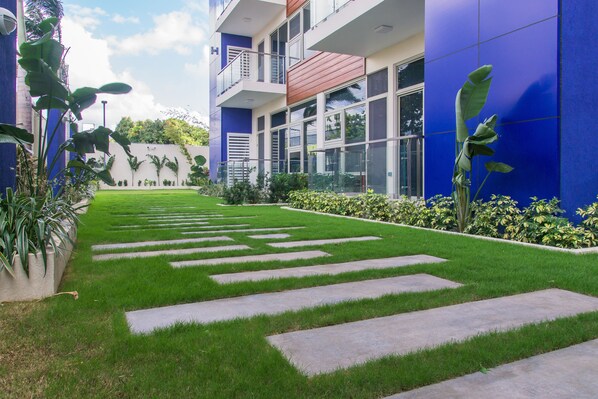 A modern building with a blue exterior, a well-maintained lawn, and a clear sky.