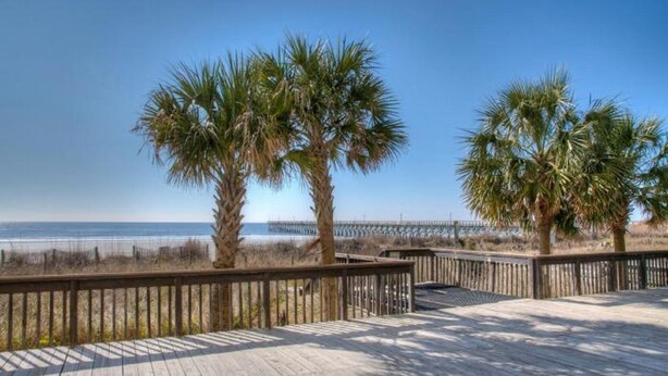 A wooden boardwalk with palm trees and a view of the ocean. - Sea Pointe 906-Oceanfront 1BR-Indoor Pool-Hot Tub (NORTH MYRTLE BEACH)