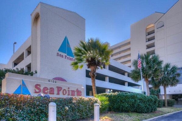 Ein Gebäude mit einem Schild, auf dem "Sea Point" steht, und eine Palme im Vordergrund.