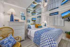 A bedroom with a bed, a chair, a dresser, and a television.