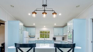 Una cocina moderna con armarios azul claro, una isla central y dos sillas negras.