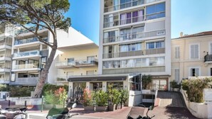 A multi-story hotel with balconies, a covered outdoor seating area, and a clear sky. - La Brise by Interhome (Cannes)