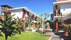 A two-story hotel with a garden courtyard, featuring a statue and tropical plants. - Santi HomeStay (Canggu)