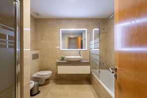 A modern bathroom with a toilet, sink, and bathtub.