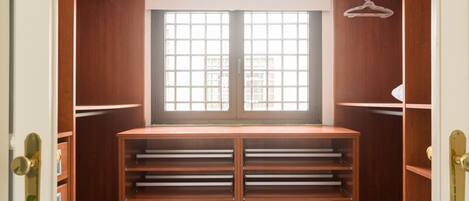 A walk-in closet with a large window, multiple shelves, and a hanging rod.
