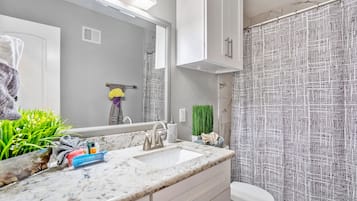 Een bad/douchecombinatie, een haardroger, handdoeken, zeep