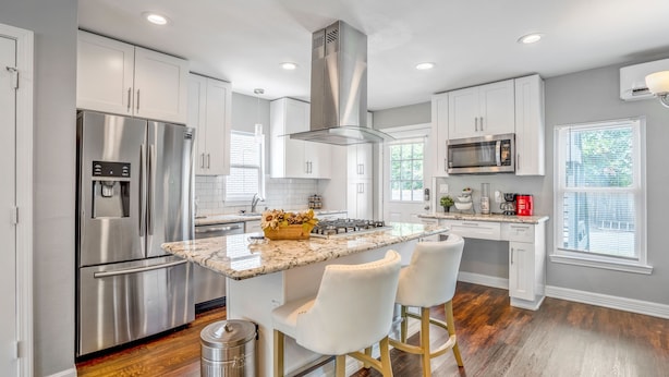 A modern kitchen with stainless steel appliances, a central island with bar stools, and a view of the outdoors. - Beautiful, Renovated, Cozy & Quiet Vacation Home in Central Houston! (Houston)