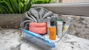 A bathroom counter with a marble surface, a towel, and various toiletries. - Beautiful, Renovated, Cozy & Quiet Vacation Home in Central Houston! (Houston)