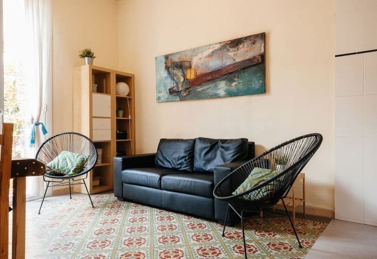 Ein Wohnzimmer mit einer Couch, zwei Sesseln, einem Bücherregal und einem Bild an der Wand.