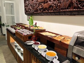 A buffet with various food items and a decorative wall piece. - Amber Angkor Villa Hotel & Spa (Siem Reap)