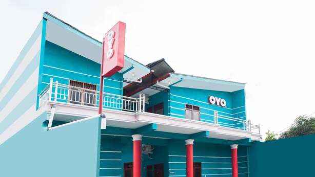 A building with a blue facade, red columns, and a balcony with a railing. - OYO 1978 Pondok Indah Residence (Medan)