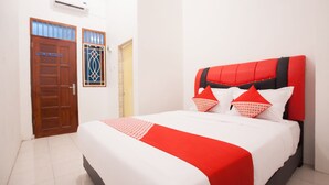 A neatly made bed with a red and white bedspread, a red headboard, and two red pillows. - OYO 1978 Pondok Indah Residence (Medan)