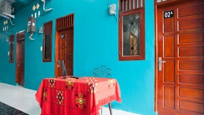A room with a teal wall, wooden doors, and a table with a red tablecloth. - OYO 1978 Pondok Indah Residence (Medan)