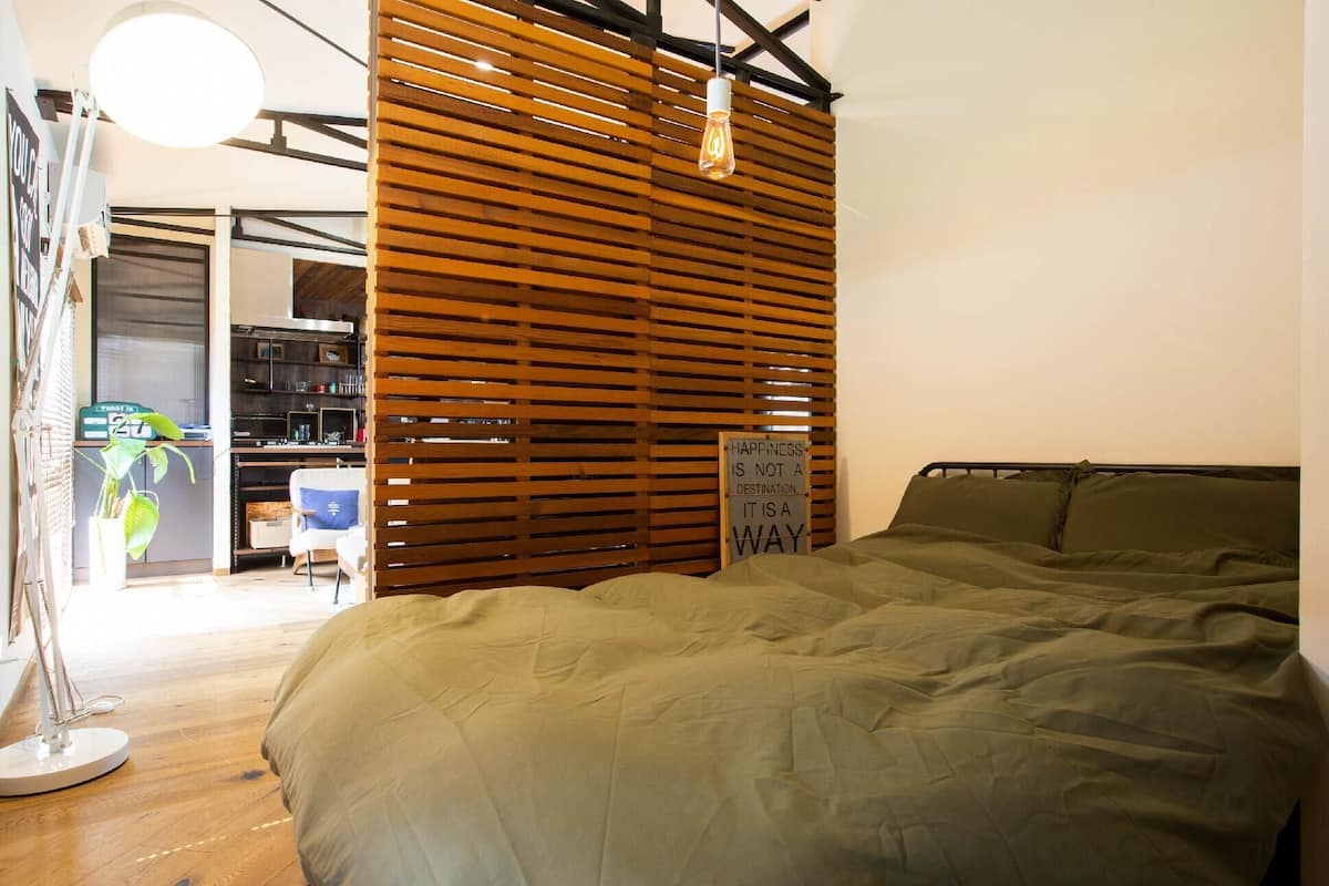 Un dormitorio con una cama, listones de madera, un cartel y un escritorio con una silla.