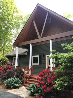 A two-story house with a wooden porch, a chimney, and a number '17' on the wall.