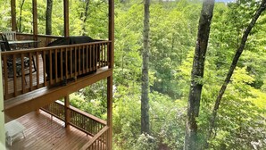 Une terrasse en bois avec des sièges extérieurs et une vue sur une forêt dense.