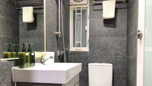 A modern bathroom with a white sink, green soap dispensers, a white toilet, and a glass shower enclosure. - Starry Inn (Kowloon)