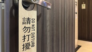 A door with a sign that reads "DO NOT DISTURB" in English and another language. - Starry Inn (Kowloon)