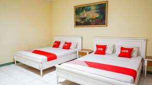 Two single beds with white frames and red bedding, a small wooden nightstand, and a painting of swans on the wall. - OYO 2085 Chrysanta Hotel (Bandung)