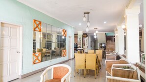 A spacious dining area with wicker furniture and a large mirror on the wall. - OYO 2085 Chrysanta Hotel (Bandung)