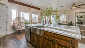 Une cuisine spacieuse avec un grand îlot central, des meubles en bois et un fauteuil suspendu.