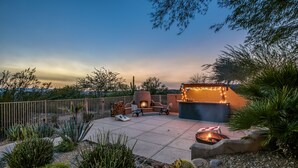 Une terrasse extérieure dotée d’un foyer, d’un espace salon et d’un éclairage décoratif.