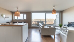 Een ruime woonruimte met een bank, eettafel en keukentrap.