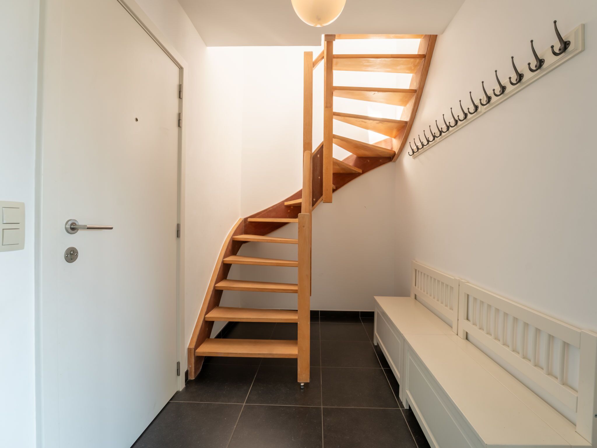 Een houten trap met een witte muur en een radiator.