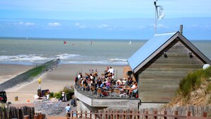 Een houten gebouw met een schuin dak, uitkijkend op een strand.