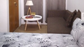 A small, well-lit room with a bed, a round table with a lamp, and a couch. - Homeystay 2 (Lapu-Lapu)