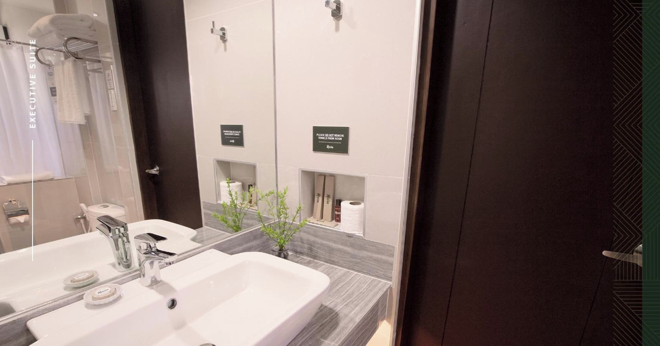 A modern bathroom with dual sinks, a large mirror, and a towel rack.
