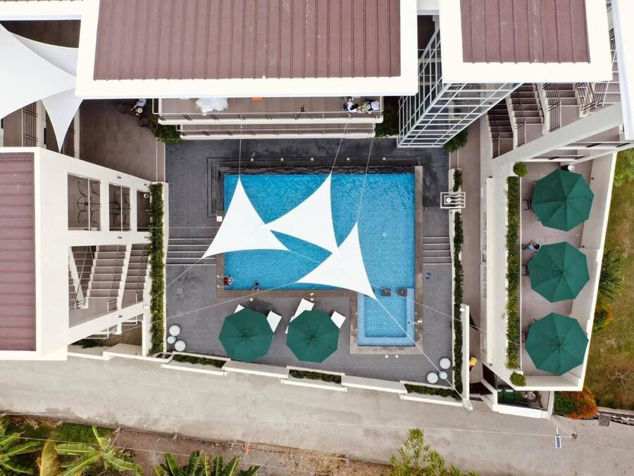 Vue aérienne d’un bâtiment moderne doté d’une piscine centrale, d’un espace de détente extérieur et d’un escalier menant à un niveau supérieur.