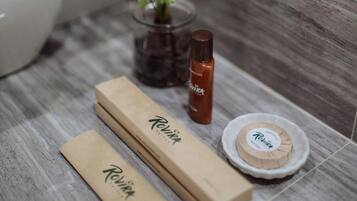 Un baño con un lavabo blanco, una pequeña planta en maceta, una botella de jabón y dos cajas de madera con la etiqueta "Revita".