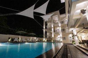 A modern hotel with a swimming pool, outdoor seating, and a multi-story structure.