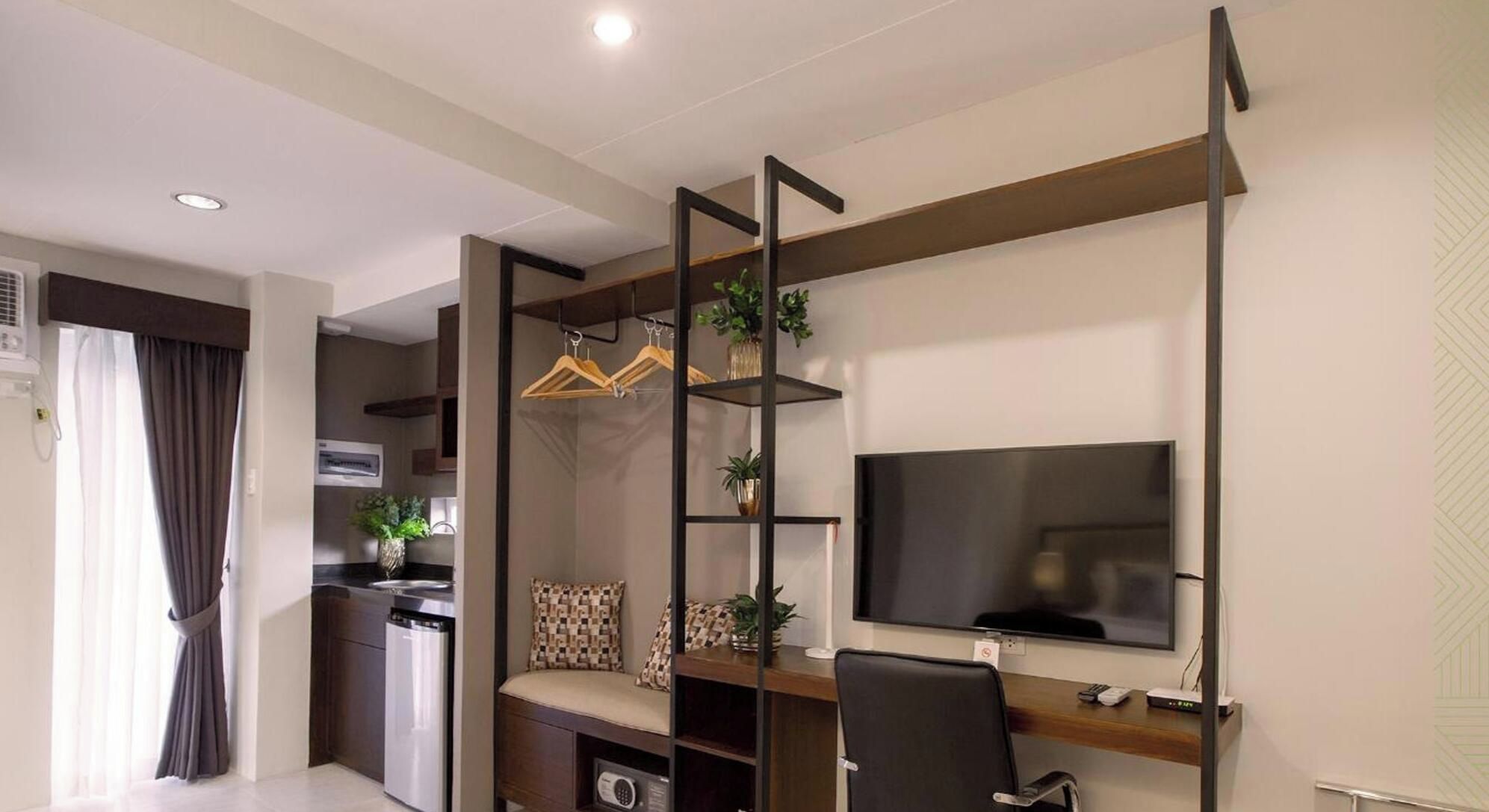 A modern living space with a kitchen, a dining area, and a seating area with a TV and desk.