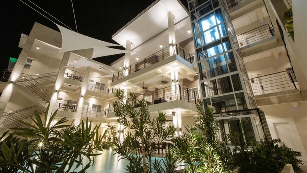 A multi-story hotel with balconies, a swimming pool, and modern architecture. - Rovira Suites (Dumaguete)