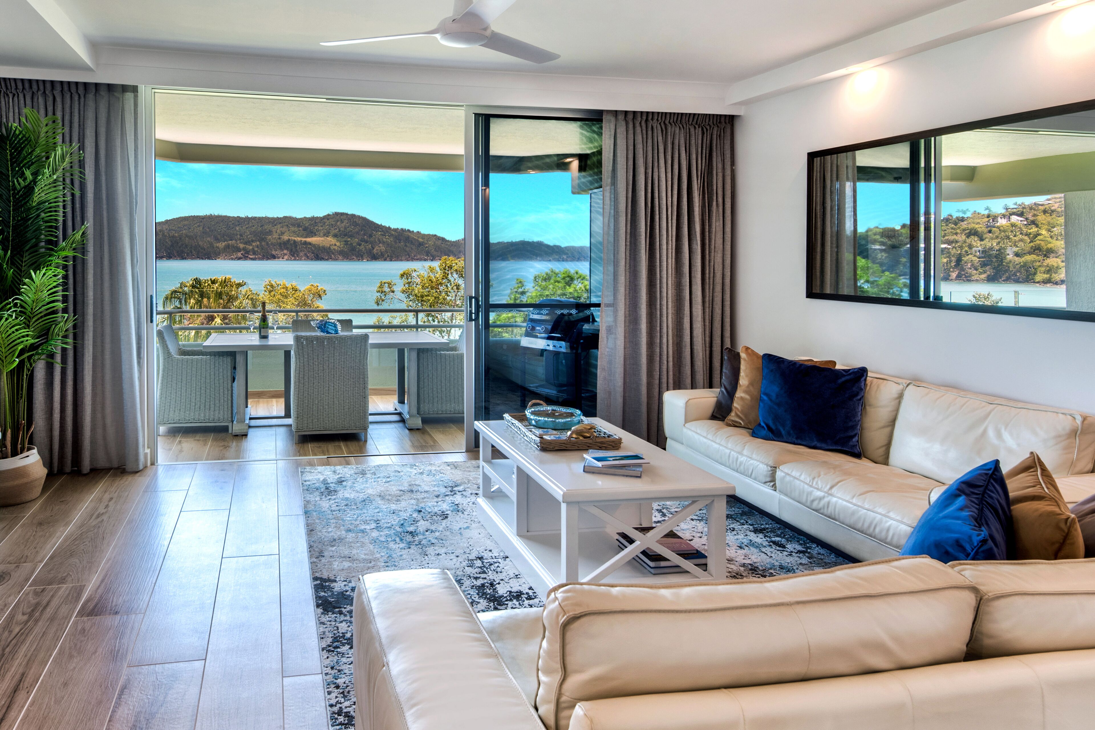 Ein modernes Wohnzimmer mit Sofa, Couchtisch und Seeblick durch große Fenster.