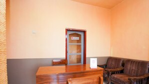 A room with a wooden table and chairs, a sofa, and a door with a sign. - OYO 1378 Tengger Indah Homestay (Ngadisari)